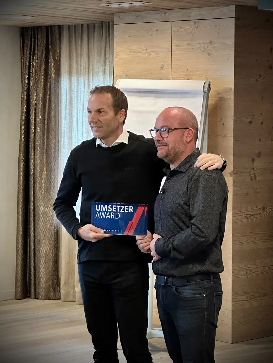 Philip Semmelroth und Daniel Rawe stehen nebeneinander und halten die Tafel des Umsetzer Awards.